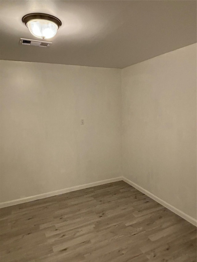 unfurnished room with wood finished floors, visible vents, and baseboards