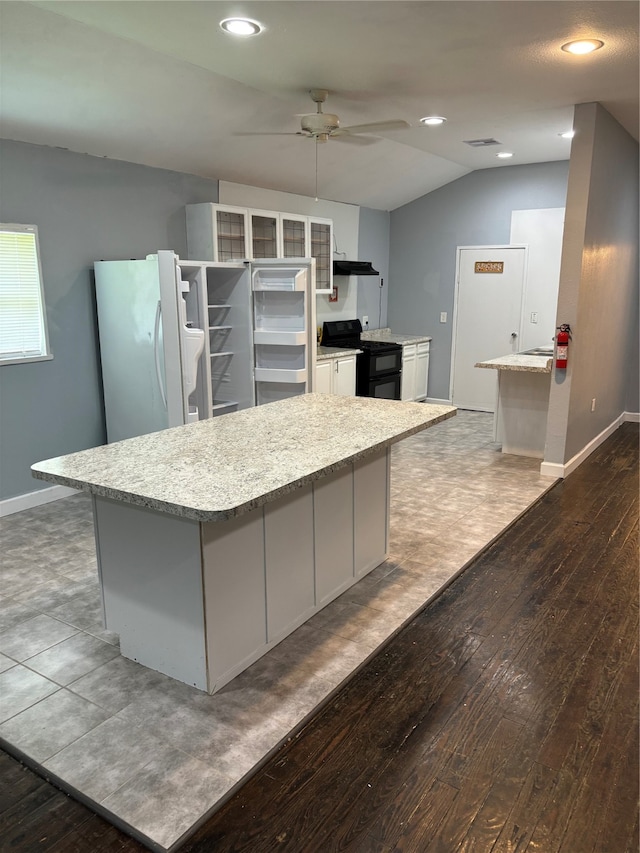 kitchen featuring dark wood-style floors, black range with gas stovetop, a ceiling fan, freestanding refrigerator, and baseboards