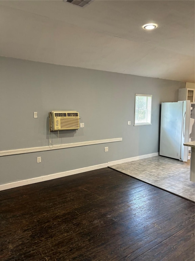 interior space with visible vents, baseboards, hardwood / wood-style floors, a wall mounted AC, and recessed lighting