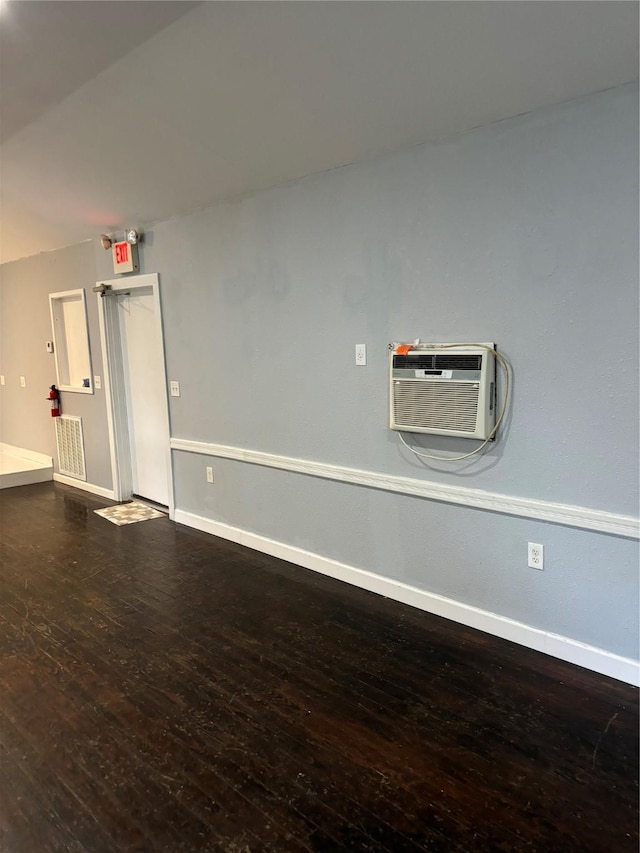 interior space featuring baseboards, an AC wall unit, and wood finished floors