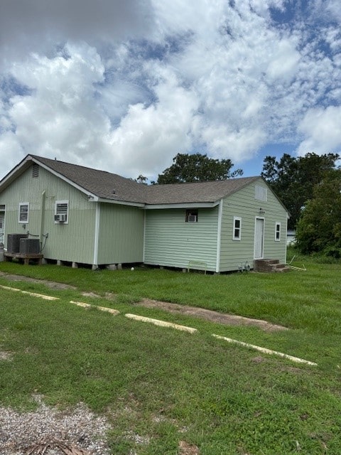 exterior space featuring central AC, a lawn, and roof with shingles