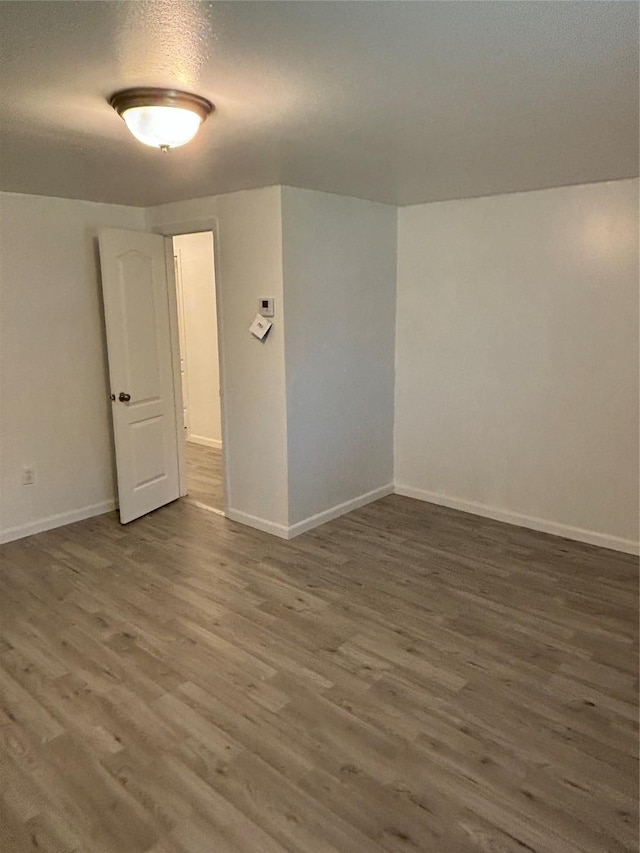 spare room featuring a textured ceiling, baseboards, and wood finished floors