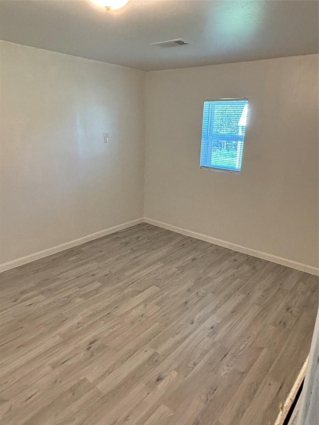 empty room featuring visible vents, baseboards, and wood finished floors