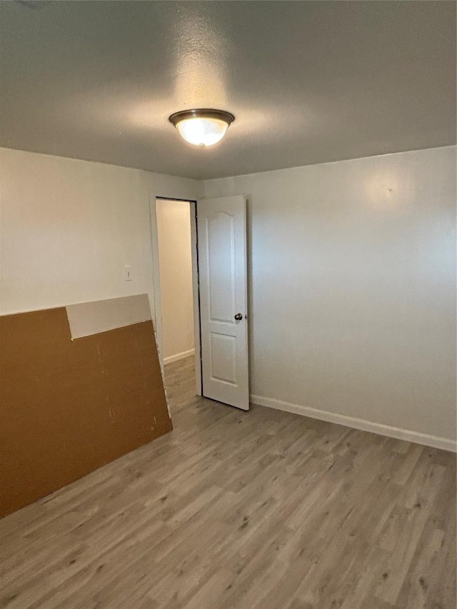 spare room featuring a textured ceiling, baseboards, and wood finished floors