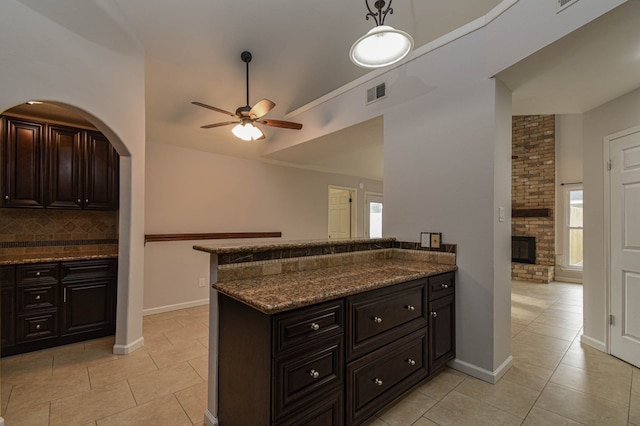 kitchen featuring a healthy amount of sunlight, dark brown cabinets, ceiling fan, and tasteful backsplash