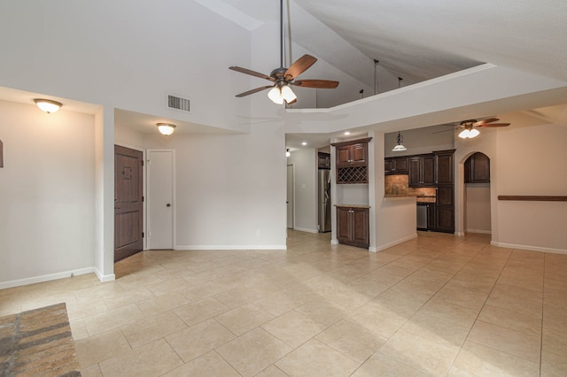 unfurnished living room with ceiling fan, light tile patterned floors, and high vaulted ceiling