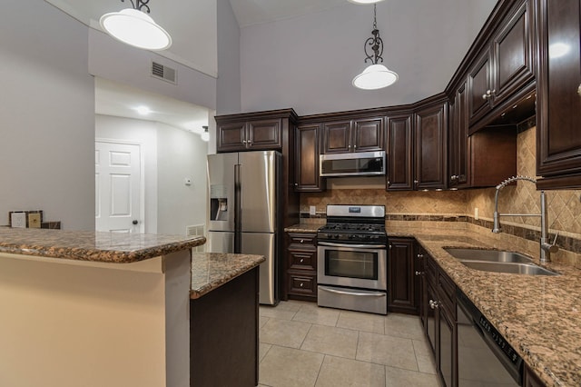 kitchen featuring dark brown cabinetry, appliances with stainless steel finishes, decorative light fixtures, and sink