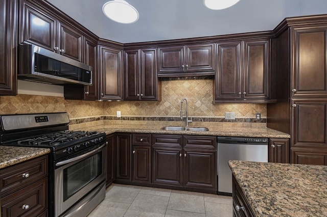 kitchen with light tile patterned flooring, stainless steel appliances, stone counters, and sink