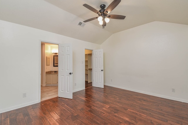 unfurnished bedroom featuring lofted ceiling, dark wood-type flooring, ceiling fan, and ensuite bath