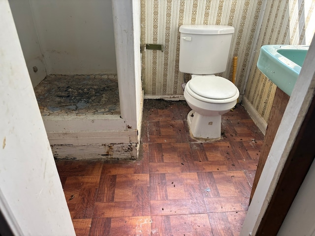 bathroom featuring parquet floors and toilet