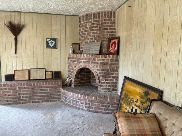 living room featuring a textured ceiling, a fireplace, and wooden walls