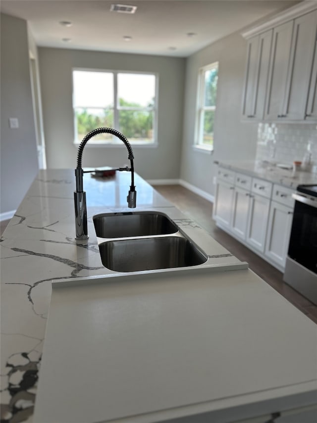 kitchen with white cabinets, stainless steel electric range oven, sink, and a kitchen island with sink