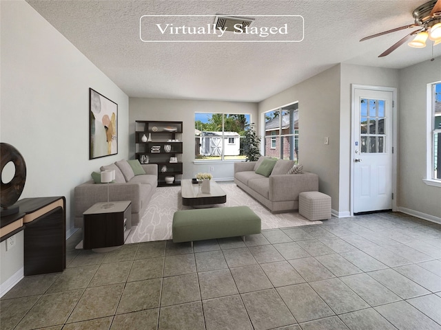 tiled living room with ceiling fan and a textured ceiling