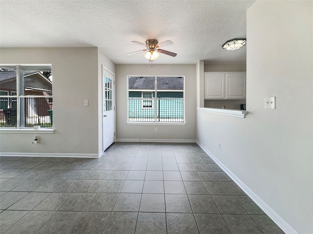 interior space with ceiling fan, plenty of natural light, tile patterned floors, and a textured ceiling