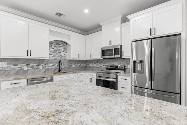 kitchen with stainless steel appliances, white cabinetry, sink, and light stone counters