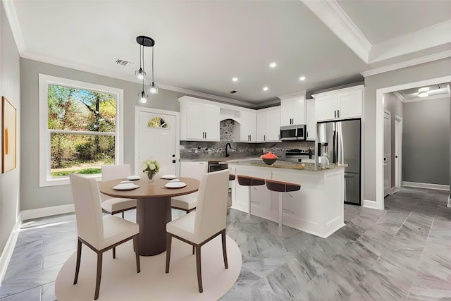 kitchen featuring decorative light fixtures, a center island, appliances with stainless steel finishes, decorative backsplash, and white cabinets