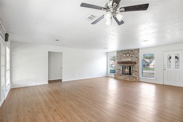 unfurnished living room with a brick fireplace, light wood-type flooring, and ceiling fan