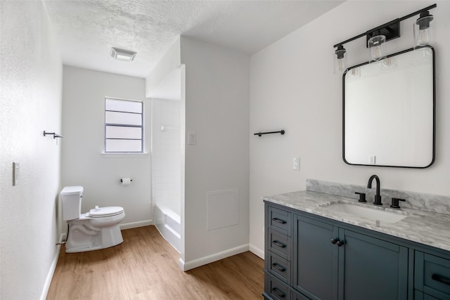 full bathroom featuring vanity, a textured ceiling, hardwood / wood-style flooring, toilet, and shower / washtub combination