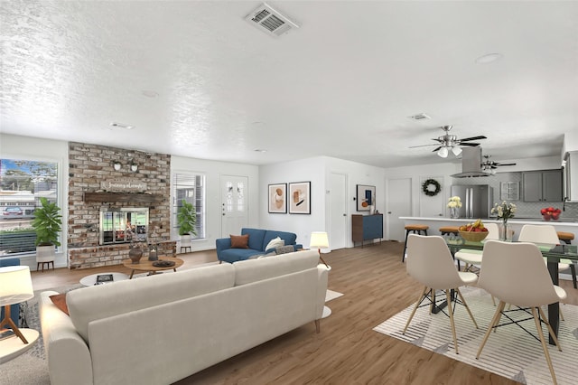 living room featuring a fireplace, ceiling fan, and light hardwood / wood-style flooring