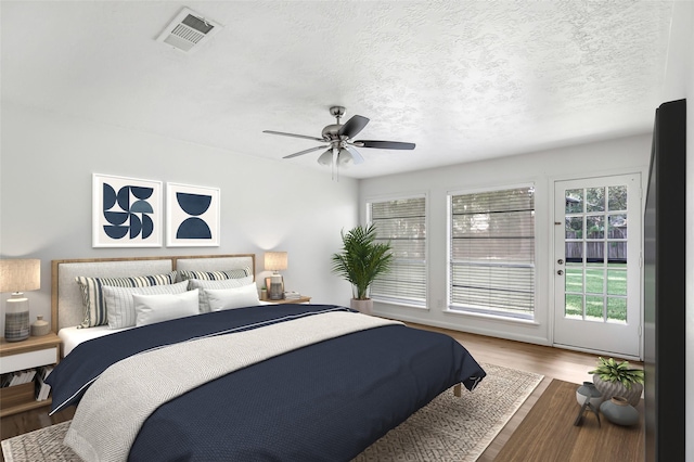 bedroom featuring access to outside, a textured ceiling, ceiling fan, and wood-type flooring