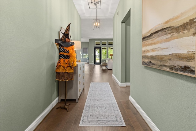 hallway with dark hardwood / wood-style floors and a notable chandelier