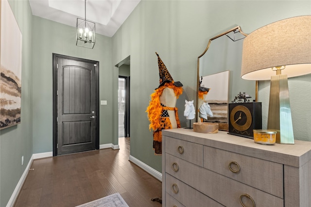 foyer entrance with an inviting chandelier and dark wood-type flooring