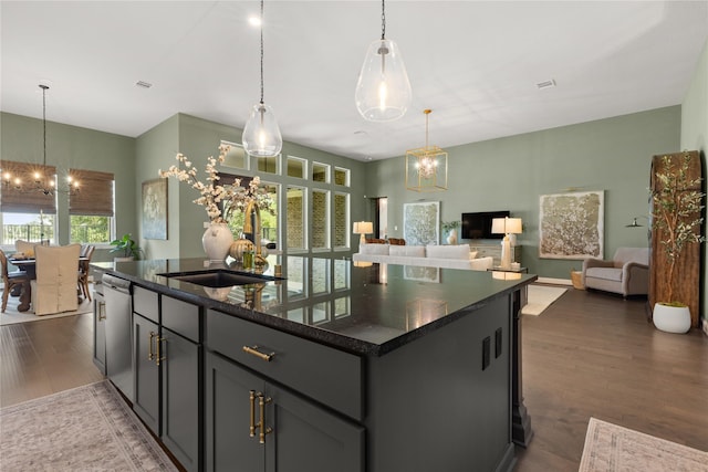 kitchen featuring stainless steel dishwasher, dark hardwood / wood-style flooring, an island with sink, a notable chandelier, and pendant lighting