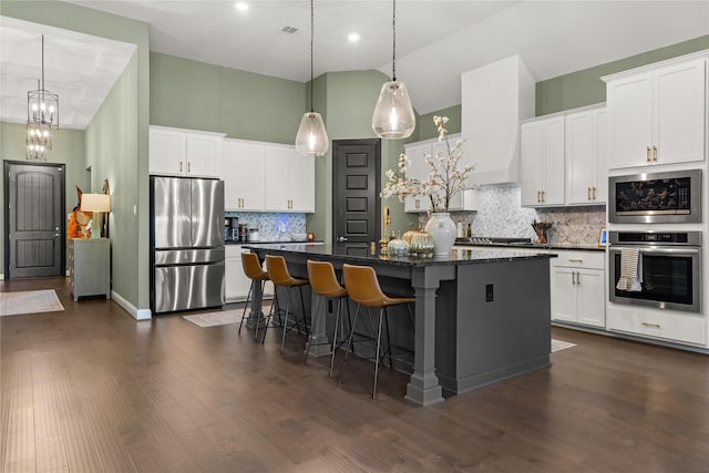 kitchen with a kitchen island, appliances with stainless steel finishes, white cabinets, and high vaulted ceiling