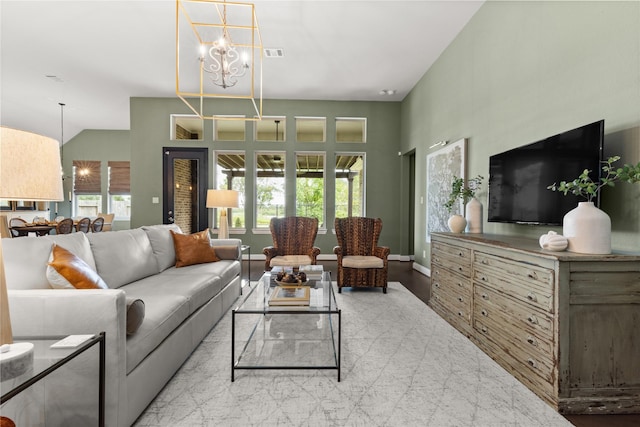 living room with vaulted ceiling, a chandelier, light hardwood / wood-style floors, and a wealth of natural light