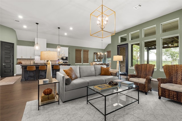 living room with lofted ceiling, light hardwood / wood-style flooring, and a notable chandelier