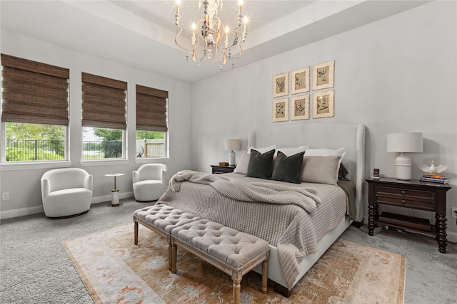 bedroom with an inviting chandelier, carpet flooring, and a raised ceiling