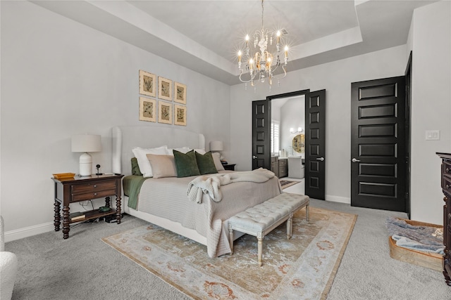 bedroom featuring connected bathroom, light carpet, a notable chandelier, and a tray ceiling