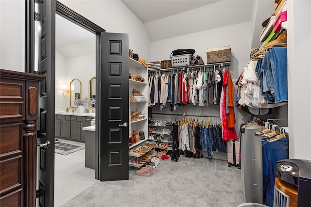 walk in closet with light colored carpet and vaulted ceiling