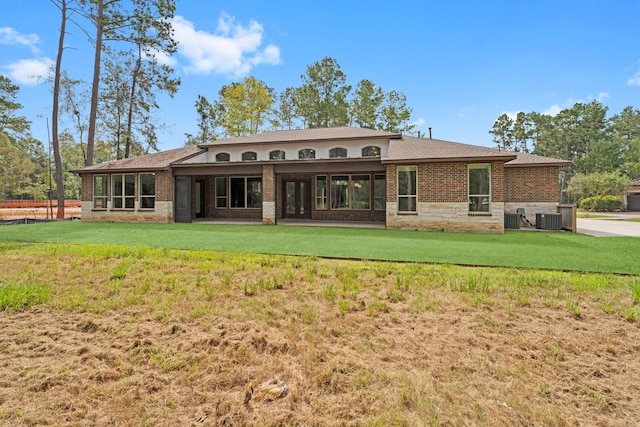 rear view of property featuring central AC unit and a lawn