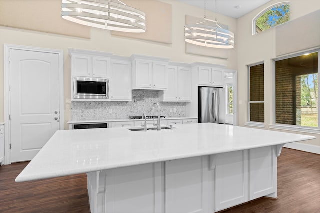 kitchen with appliances with stainless steel finishes, white cabinetry, and an island with sink