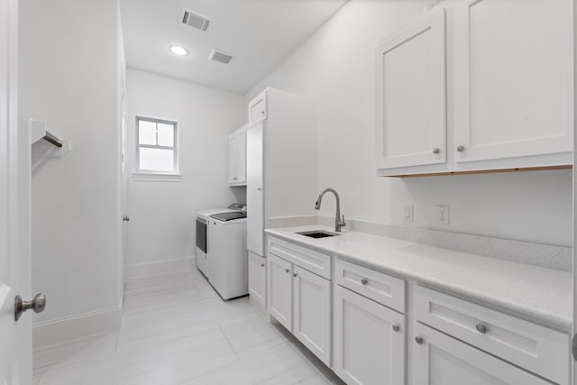 laundry area with cabinets, washing machine and dryer, and sink