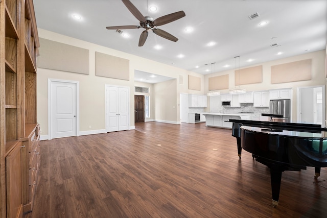 kitchen with ceiling fan, white cabinets, pendant lighting, stainless steel fridge, and a kitchen island