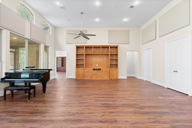 playroom featuring ceiling fan, a towering ceiling, and dark wood-type flooring