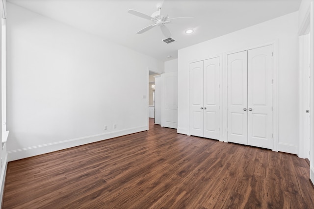 unfurnished bedroom featuring ceiling fan, two closets, and dark hardwood / wood-style flooring