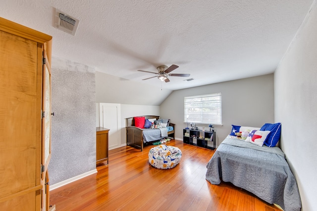 living room featuring vaulted ceiling, ceiling fan, hardwood / wood-style floors, and a textured ceiling