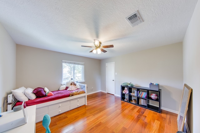 bedroom with a textured ceiling, hardwood / wood-style floors, and ceiling fan