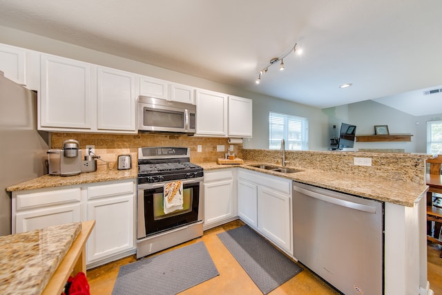 kitchen with sink, white cabinets, kitchen peninsula, decorative backsplash, and stainless steel appliances