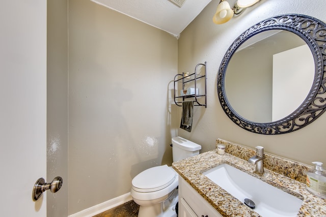 bathroom featuring a textured ceiling, vanity, and toilet