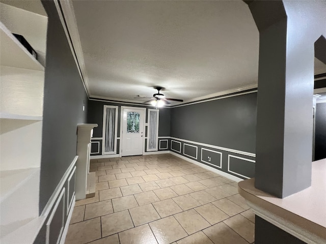 spare room with a textured ceiling, ceiling fan, light tile patterned flooring, and crown molding