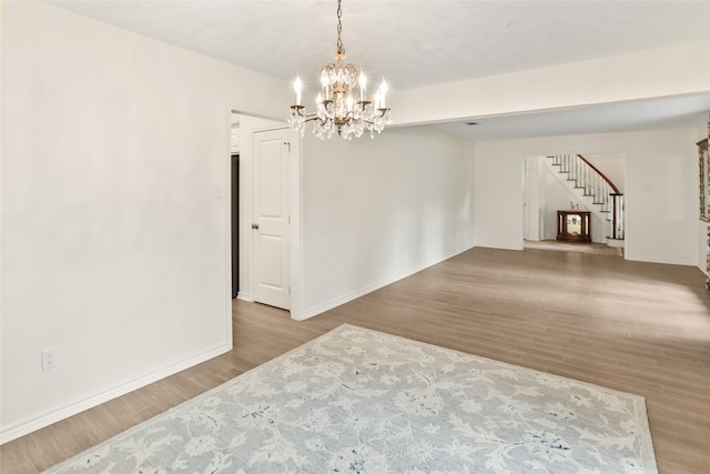 empty room with light hardwood / wood-style floors and a notable chandelier