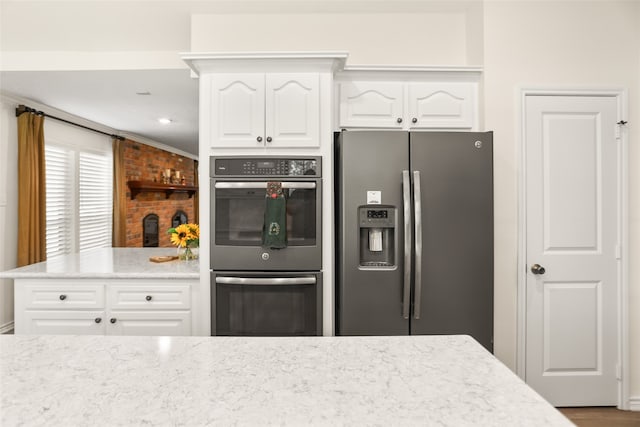 kitchen featuring light stone countertops, stainless steel appliances, crown molding, and white cabinetry