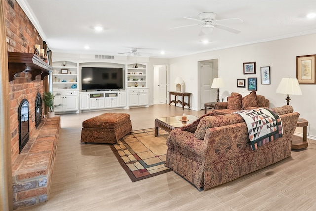 living room featuring light wood-type flooring, ceiling fan, a fireplace, and crown molding