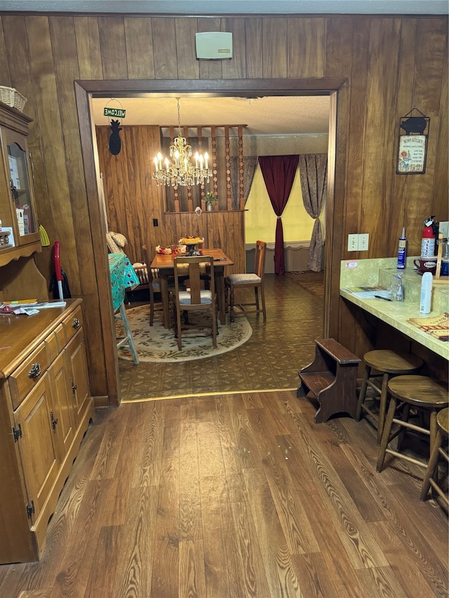 dining room with an inviting chandelier, wooden walls, and dark hardwood / wood-style flooring