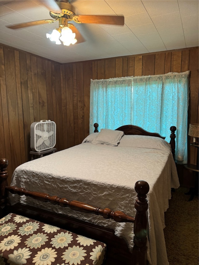 bedroom featuring wooden walls, ceiling fan, and carpet flooring