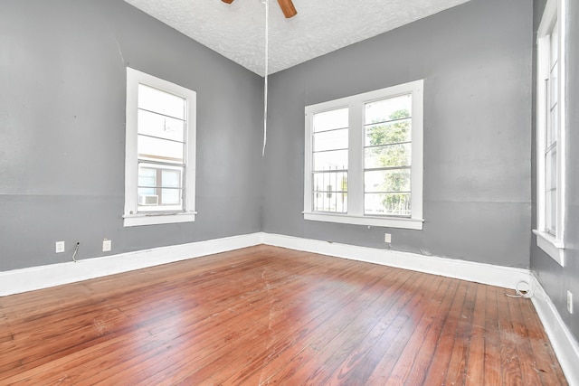 unfurnished room with a textured ceiling, vaulted ceiling, hardwood / wood-style floors, and ceiling fan